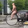 Bald man in leopard print leotard spotted riding Victorian-era bicycle through downtown Seattle in rainy weather