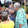 From left, Kim Mooney, Mike Mooney, Emma Welsch and Bob Welsch listen as Joe Sears, center, shows off a one-string cigar box guitar.